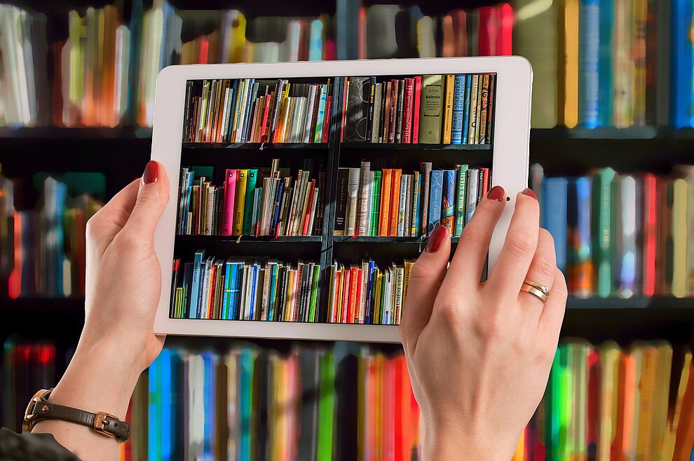 Tablet fotografiert Bücher aus dem Bücherregal Tablet fotografiert Bücher aus dem Bücherregal